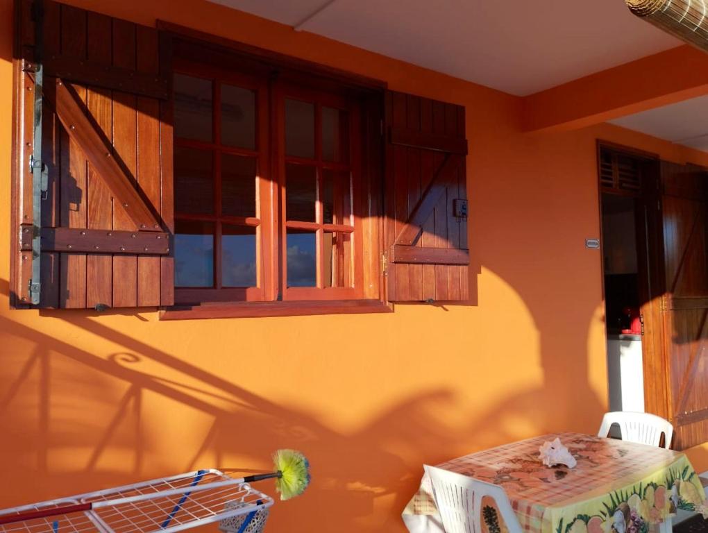 an orange room with a table and windows at Appartement de 2 chambres avec vue sur la mer terrasse amenagee et wifi a Bouillante a 4 km de la plage in Bouillante