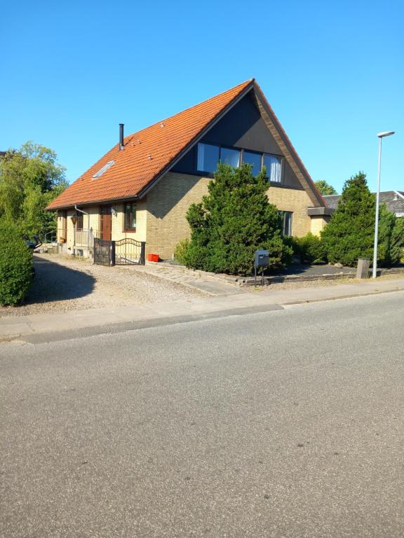 uma casa com um telhado vermelho na berma da estrada em Vila Alexandra em Bække