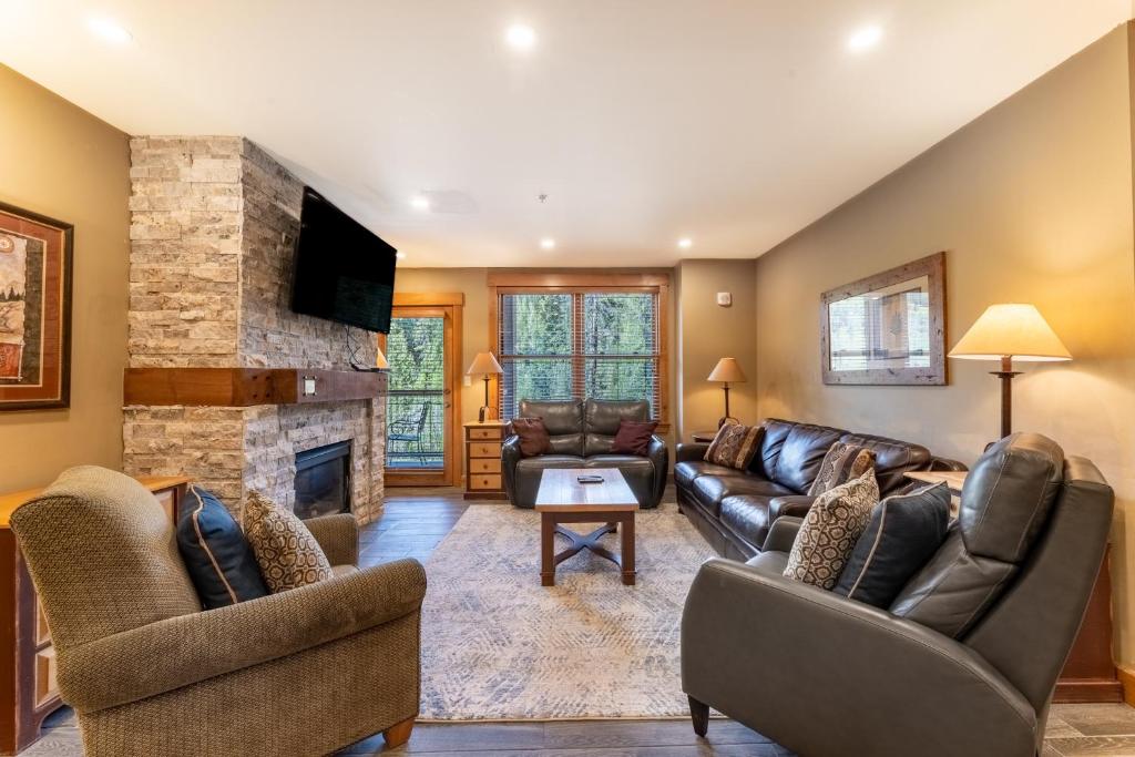 a living room with leather furniture and a stone fireplace at Springs by Summit County Mountain Retreats in Keystone