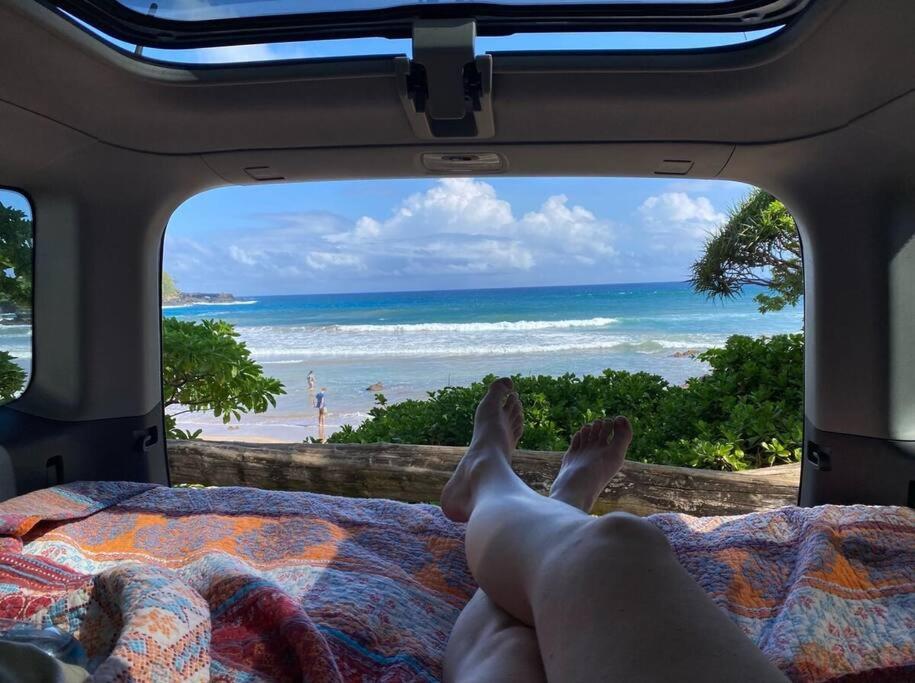 eine Person auf einem Bett mit Blick auf den Strand in der Unterkunft Campervan/Maui hosted by Go Camp Maui in Kihei