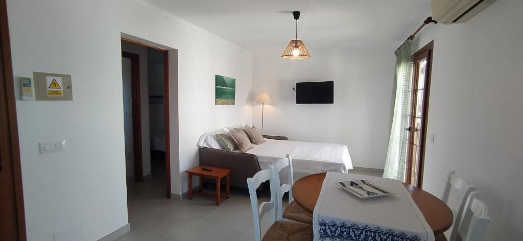 a small white room with a bed and a table at Apartamentos Villa Primera in Cala Figuera