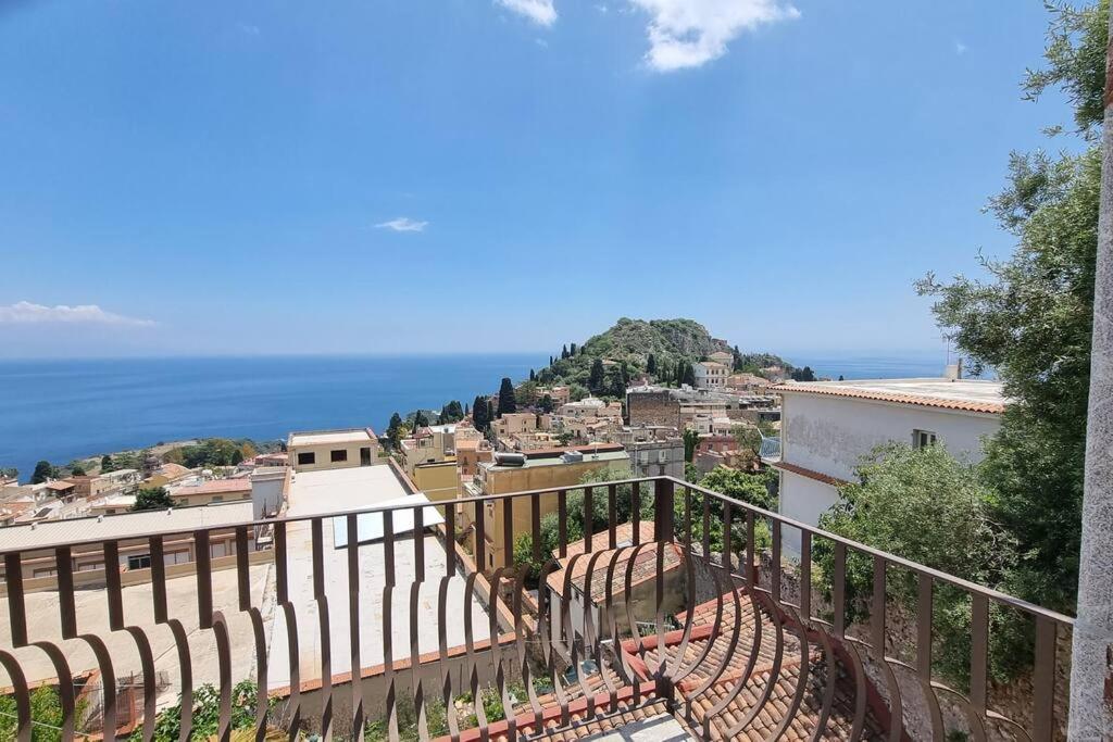 a balcony with a view of a city and the ocean at PHS Panoramic House Suite in Taormina