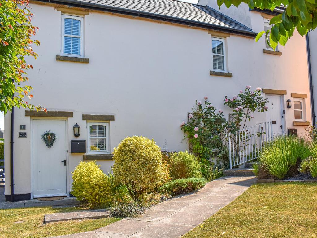 a white house with a white door and a yard at Cosy Cottage in Holker