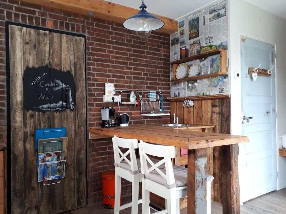 a kitchen with a wooden counter and a brick wall at Tiny home Texel in Den Burg
