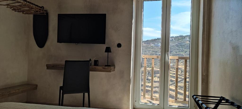 a bedroom with a television and a view of a balcony at ClockWise Earthy Vibe House in Apano Chora in Ano Syros