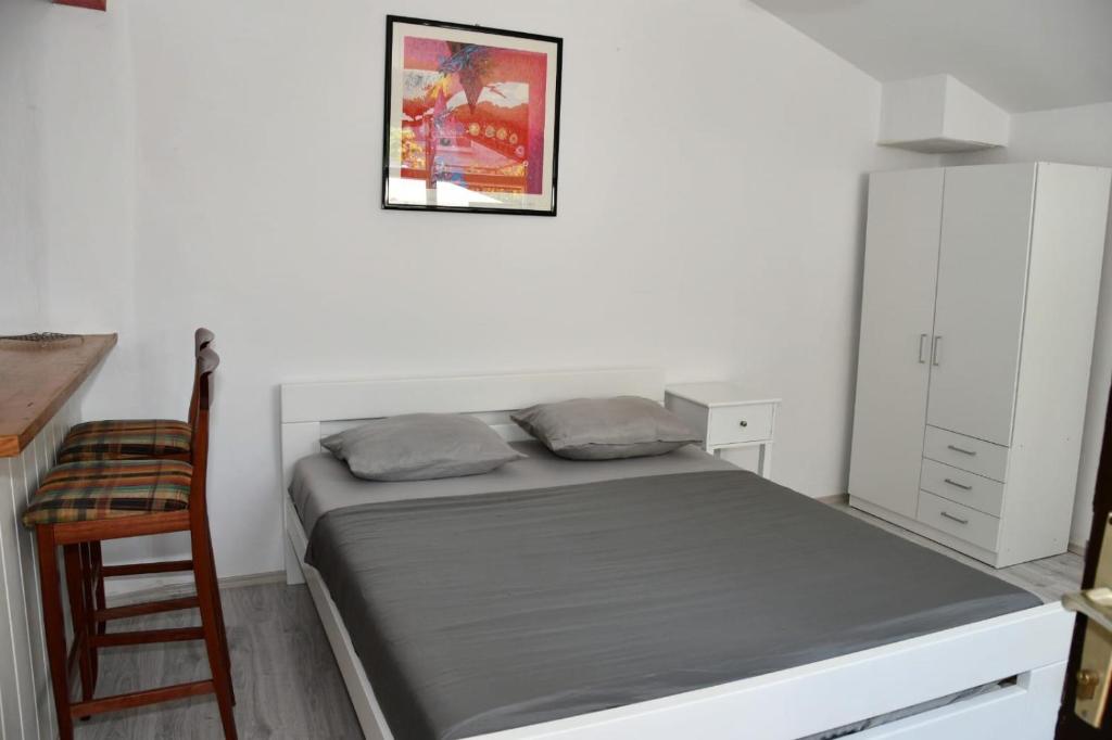 a small bedroom with a bed and a chair at Apartmani Katarina in Biograd na Moru