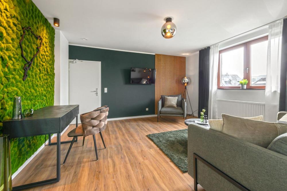 a living room with a couch and a green wall at Hotel Zweite Heimat Nürburg in Kelberg