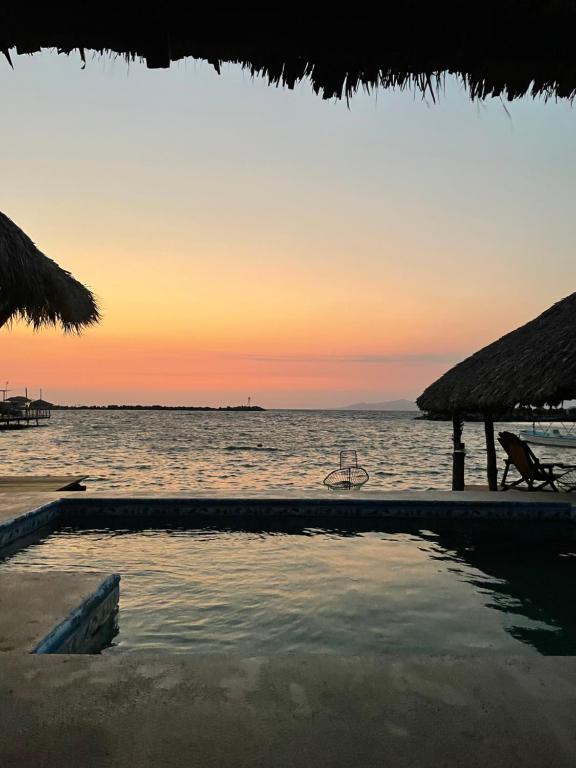 ein Pool am Strand bei Sonnenuntergang in der Unterkunft Hotel Coconuts in Tecpan de Galeana