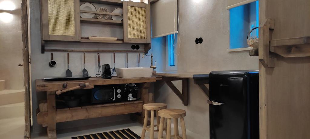 a kitchen with a black refrigerator and wooden stools at ClockWise Earthy Vibe House in Apano Chora in Ano Syros
