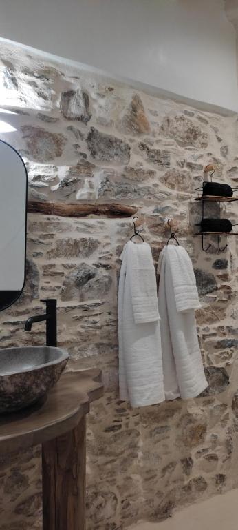 a bathroom with white towels hanging on a stone wall at ClockWise Earthy Vibe House in Apano Chora in Ano Syros
