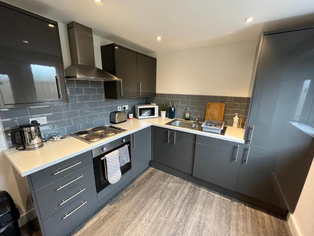 una cucina con armadi grigi, lavandino e forno a microonde di Modern Serviced Apartment - Near City Centre a Doncaster