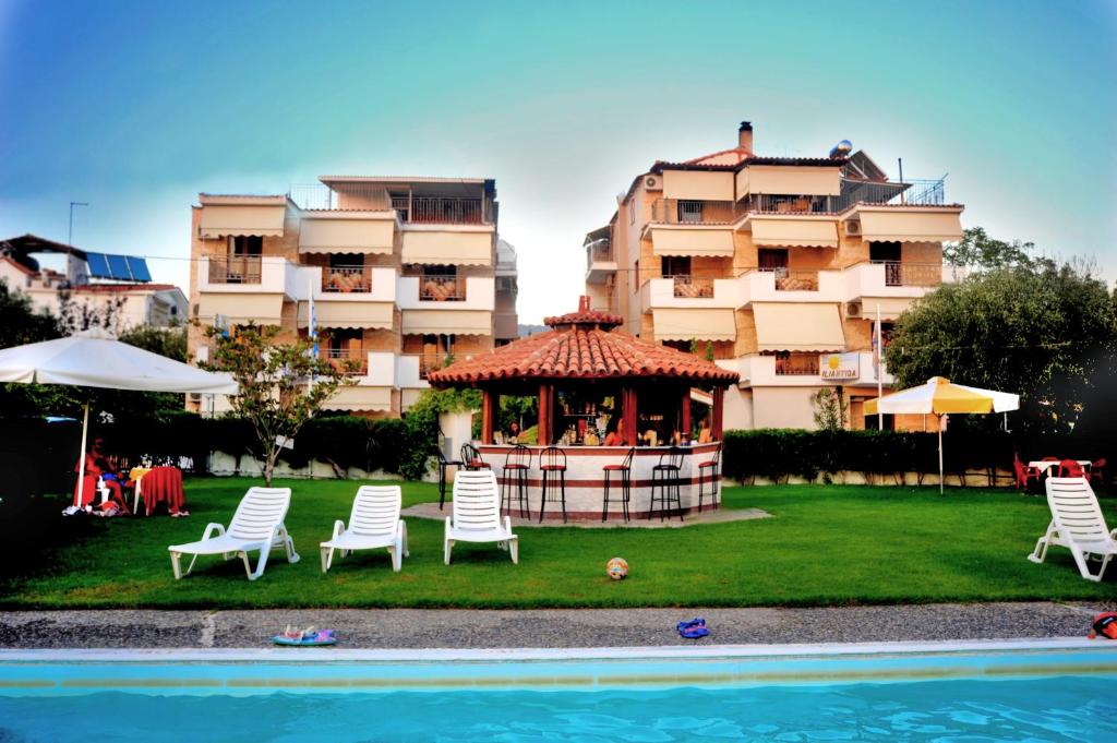 a gazebo in front of a building next to a pool at Iliahtida Apartments in Rovies