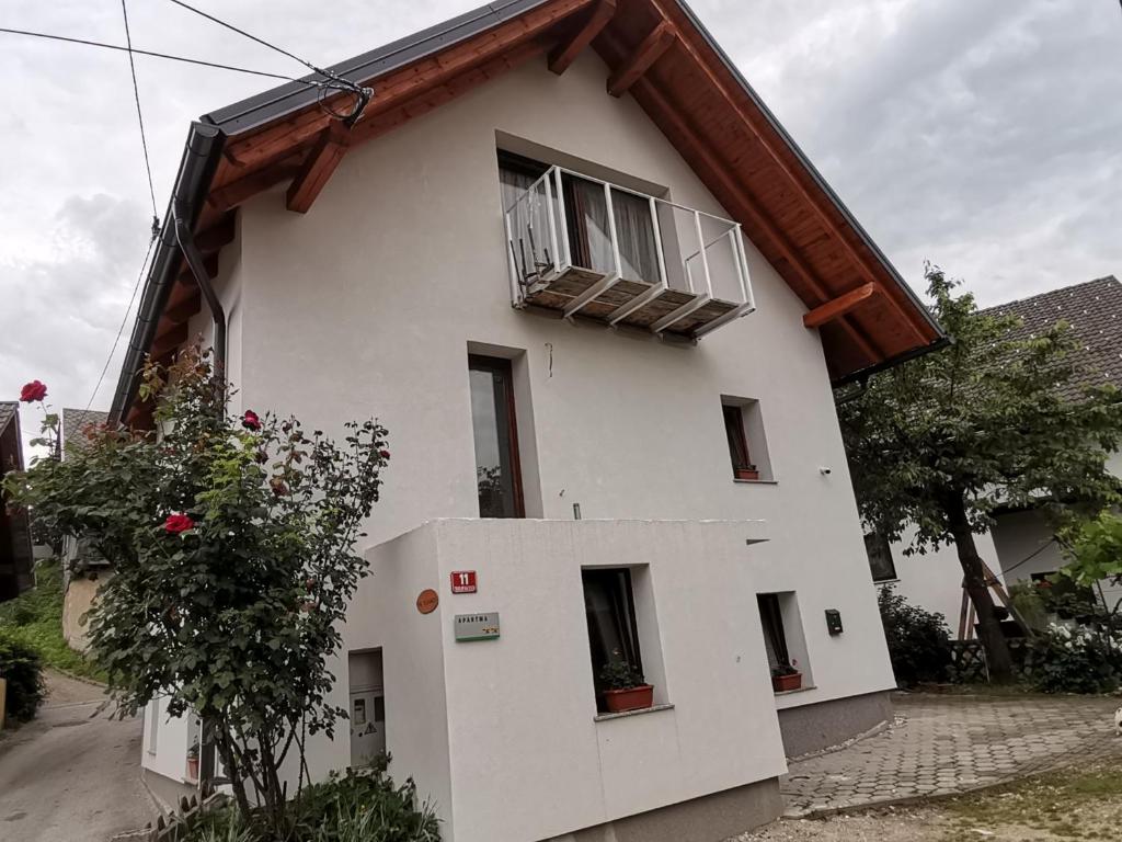 a white house with a window and a balcony at Apartment PIKAPOLONICA in Bled