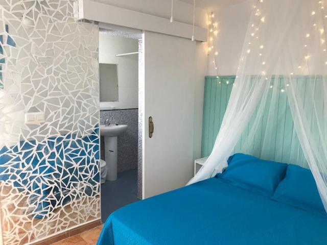 sypialnia z niebieskim łóżkiem i łazienką w obiekcie Petit Room, Habitación w mieście Conil de la Frontera