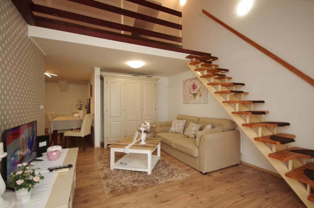 a living room with a couch and a spiral staircase at Gyulai idill apartman in Gyula