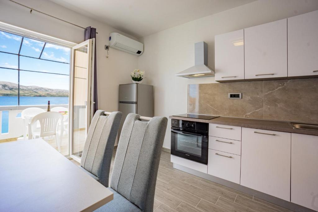 een keuken met witte kasten en een tafel met stoelen bij Bepo Apartments at beach in Metajna