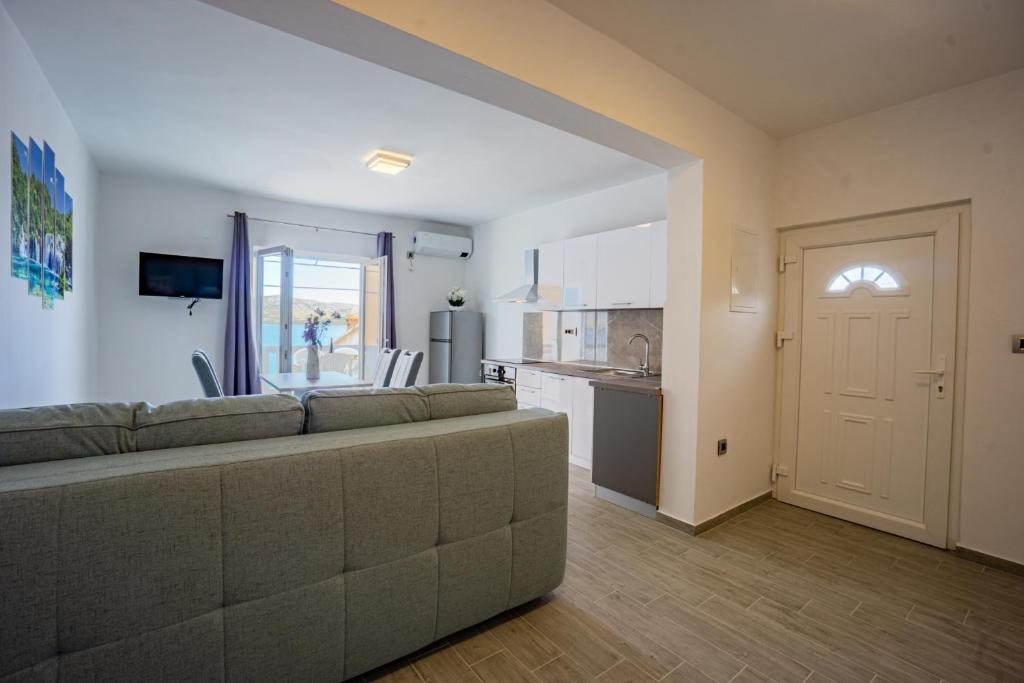 een woonkamer met een bank en een keuken bij Bepo Apartments at beach in Metajna