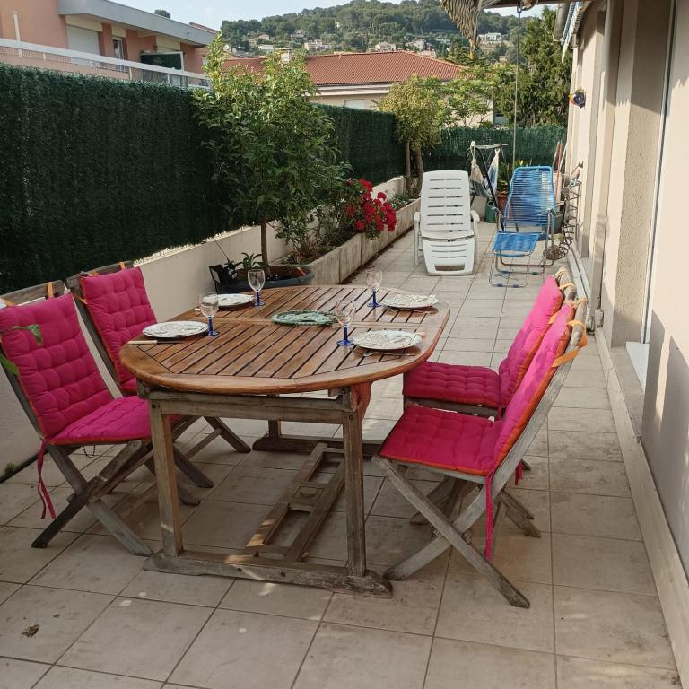 une table en bois avec des chaises roses sur la terrasse dans l'établissement Apartment near the center of Vallauris, à Vallauris