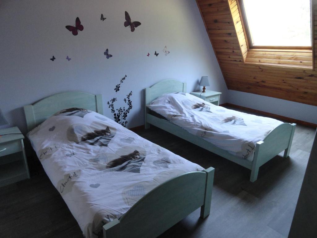 two beds in a room with butterflies on the wall at GÏTE LA DANSE DES BICHES in Ranspach