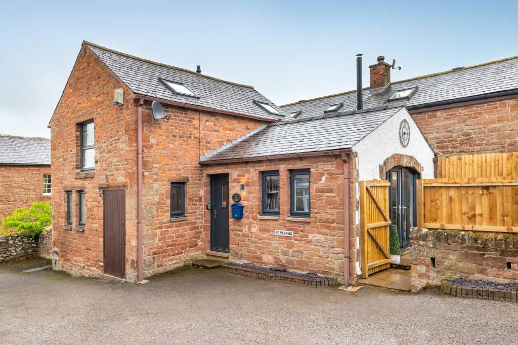 an old brick building with a gate and a garage at Beautiful 2-Bed Cottage in Brampton in Brampton