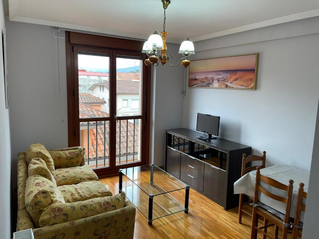 uma sala de estar com um sofá, uma mesa e uma televisão em APARTAMENTO RIO SELLA em Arriondas