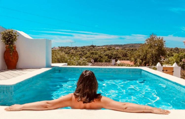 a woman laying on the edge of a swimming pool at Casa na Colina : The Cottage and The Long House in São Brás de Alportel