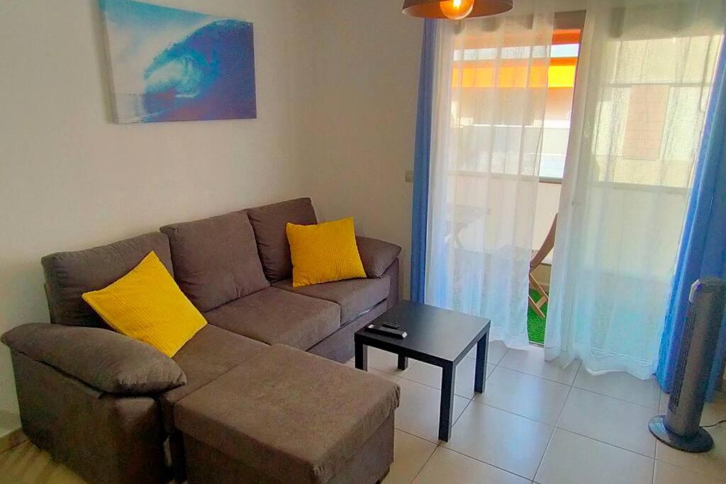 un soggiorno con divano marrone e cuscini gialli di Alcalá Center Playa a Alcalá