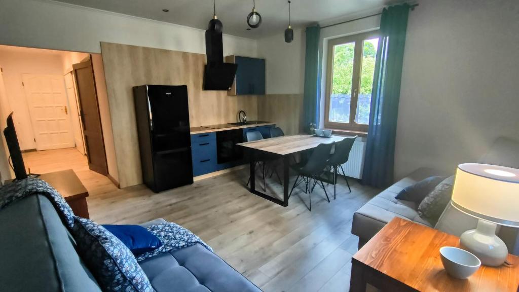 a living room with a couch and a table and a kitchen at Apartament Pod Czereśnią in Suwałki