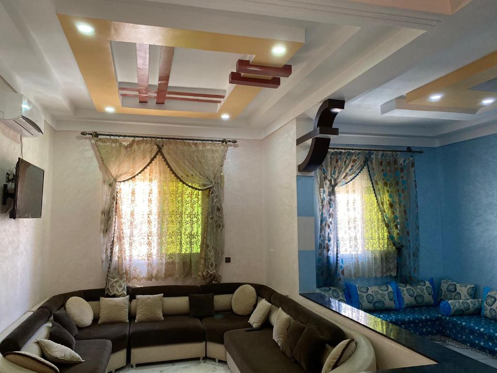 een woonkamer met een bank en 2 ramen bij Appartement Ouargaga in Meknès