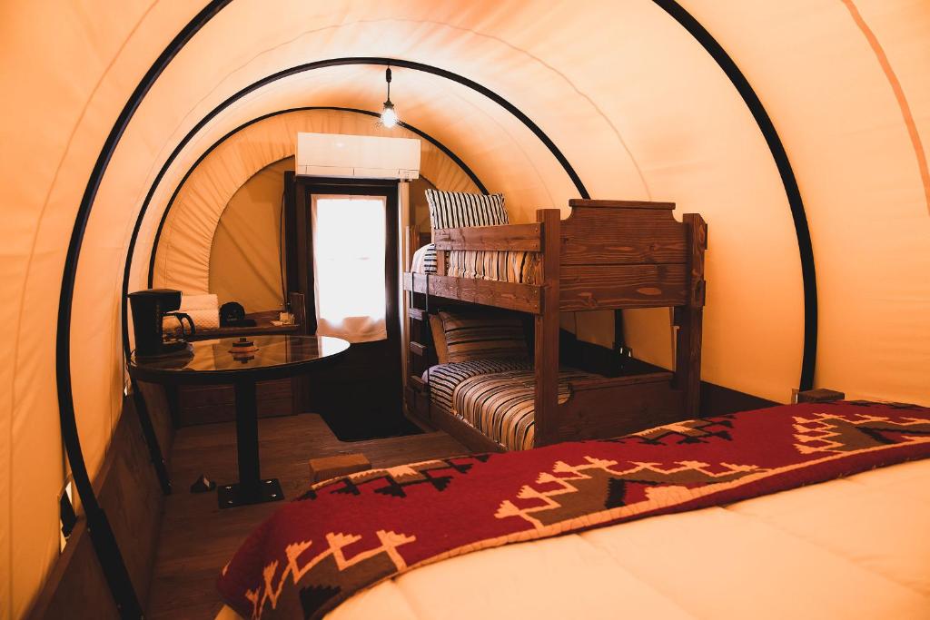 Una habitación con una cama y una mesa en una tienda de campaña en The Big Texan - Cabins and Wagons, en Amarillo