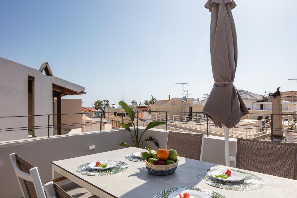 a table with a bowl of fruit and an umbrella on a balcony at Anchel maison in Rethymno Town