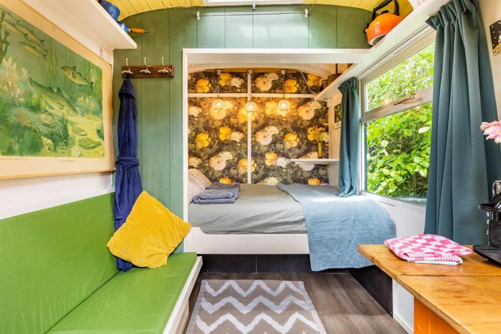 een groene en witte kamer met een bed en een raam bij Tiny House in Kampen