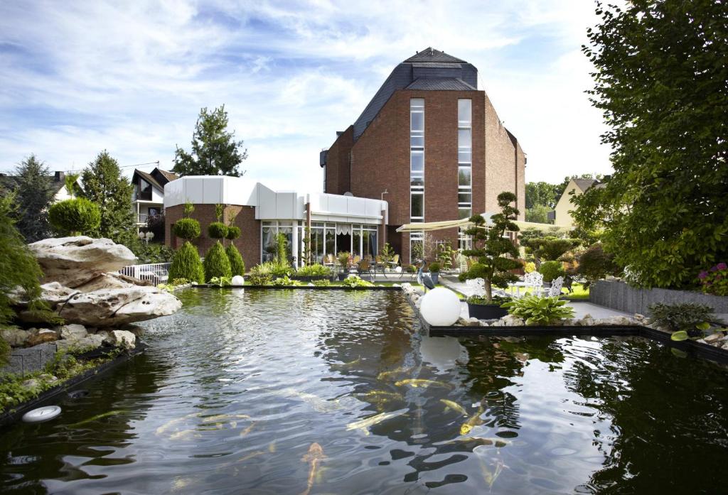 a building with a pond in front of a building at Rheinhotel Larus in Kaltenengers