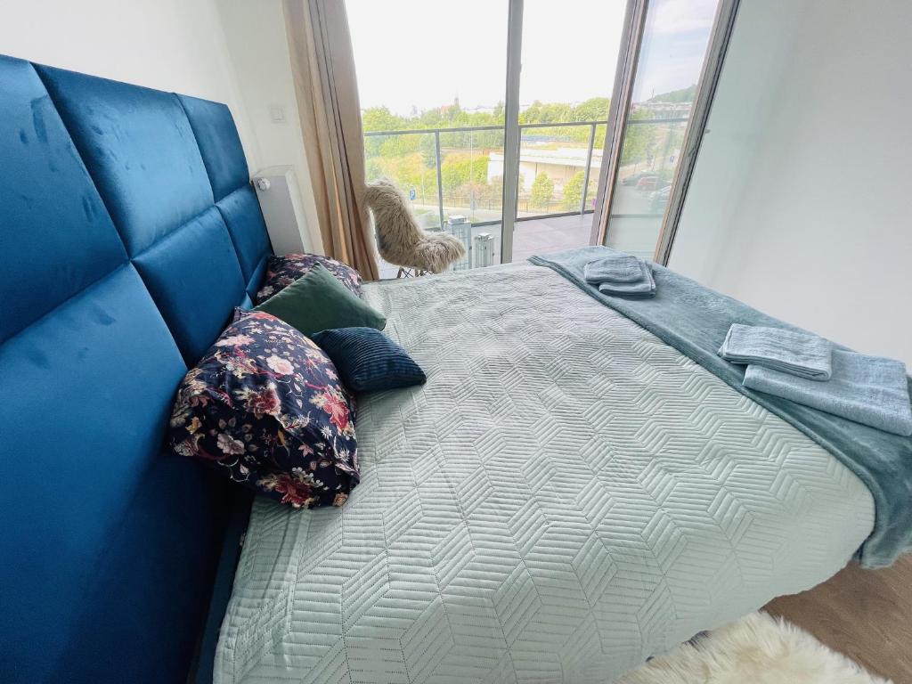 niebieskie łóżko w pokoju z oknem w obiekcie Apartament Arena Gdynia w mieście Gdynia