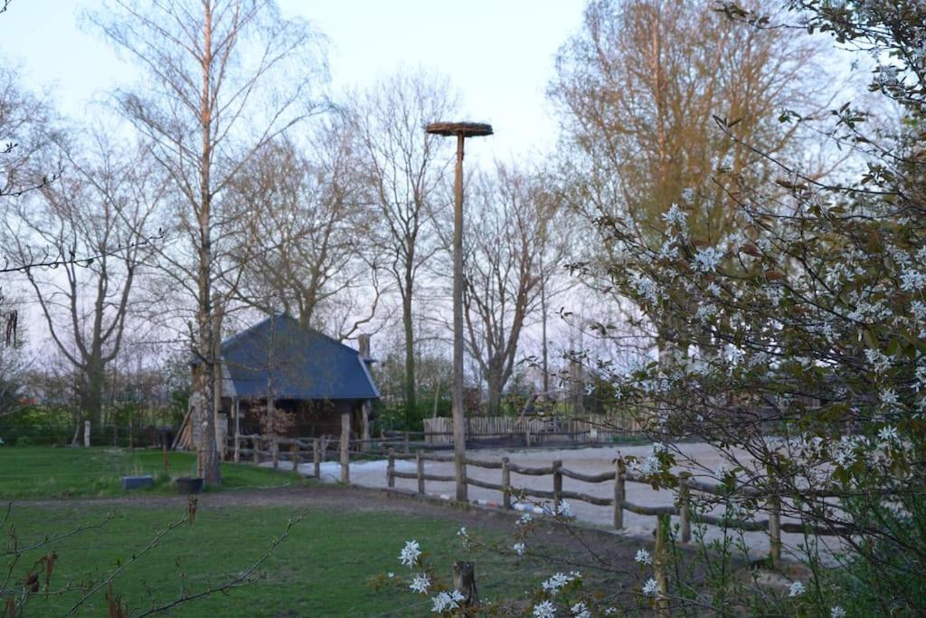 um parque com uma cerca de madeira e um celeiro em Nostalgisch overnachten in hooimijt 