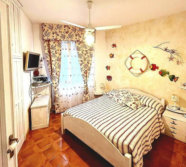 a bedroom with a bed and a tv and a window at Alghero Sa Stella Casa Vacanze in Fertilia