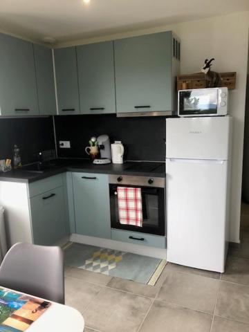 cocina con armarios blancos, microondas y horno en Location appartement T2 - 1 chambre le bourget du lac, en Le Bourget-du-Lac