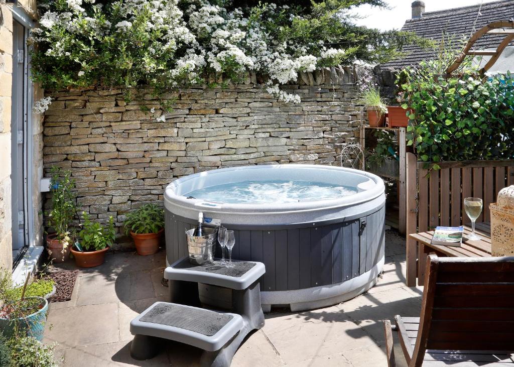 a hot tub in a yard with a brick wall at Castle Hideaway in the Cotswolds in Chipping Campden
