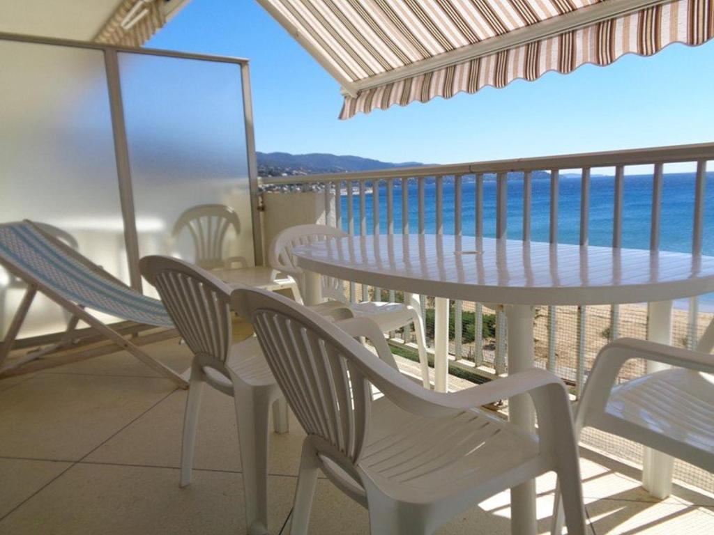 un balcon avec une table et des chaises et l'océan dans l'établissement Studio bien équipé en bord de mer avec terrasse - Le Lavandou - FR-1-308-43, au Lavandou