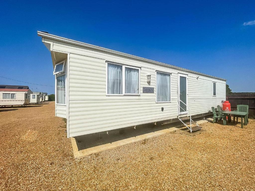 a small white trailer with a bench and a house at 4 Berth Nearby Hunstanton Beach In Norfolk Ref 13018l in Hunstanton