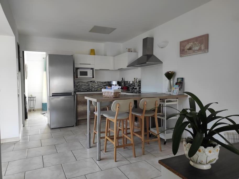 une cuisine avec une table, des chaises et un réfrigérateur dans l'établissement Joli appartement avec cour privé à 5 minutes à pied de la plage, à Sanary-sur-Mer