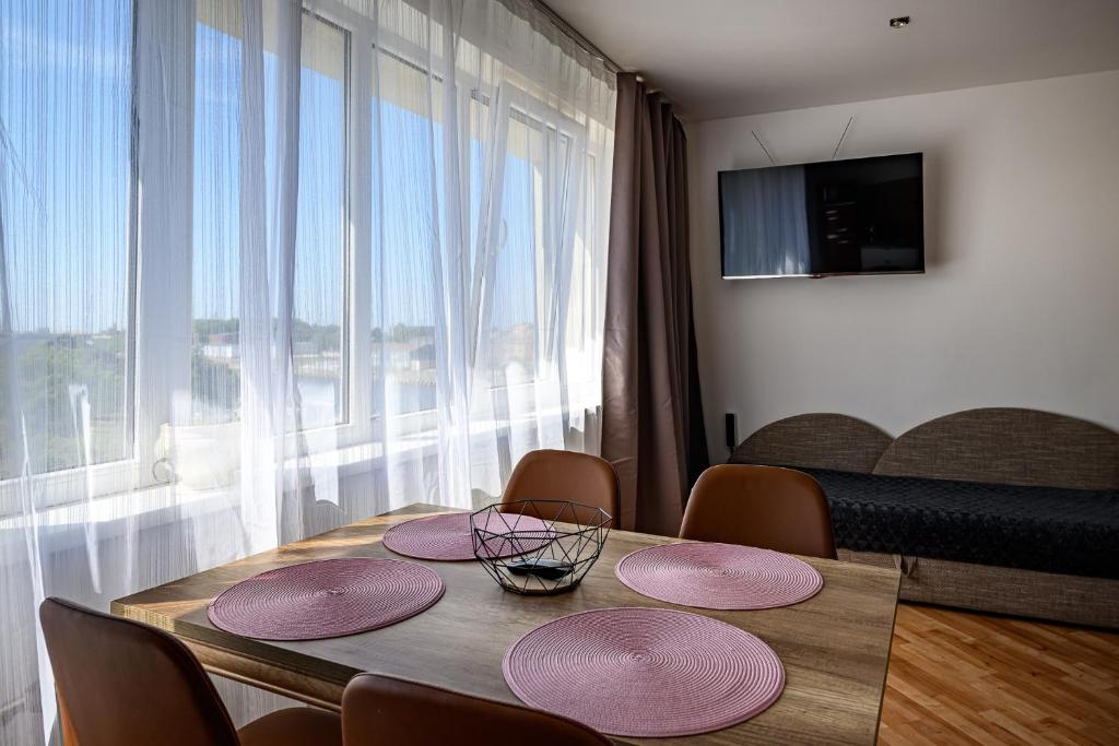 a dining room table with four pink plates on it at SUNSET urban apartment in Liepāja