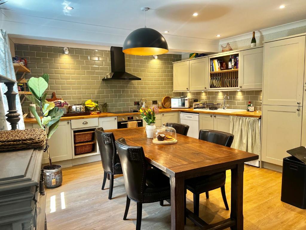 a kitchen with a wooden table and black chairs at Olive Tree Cottage in Rye