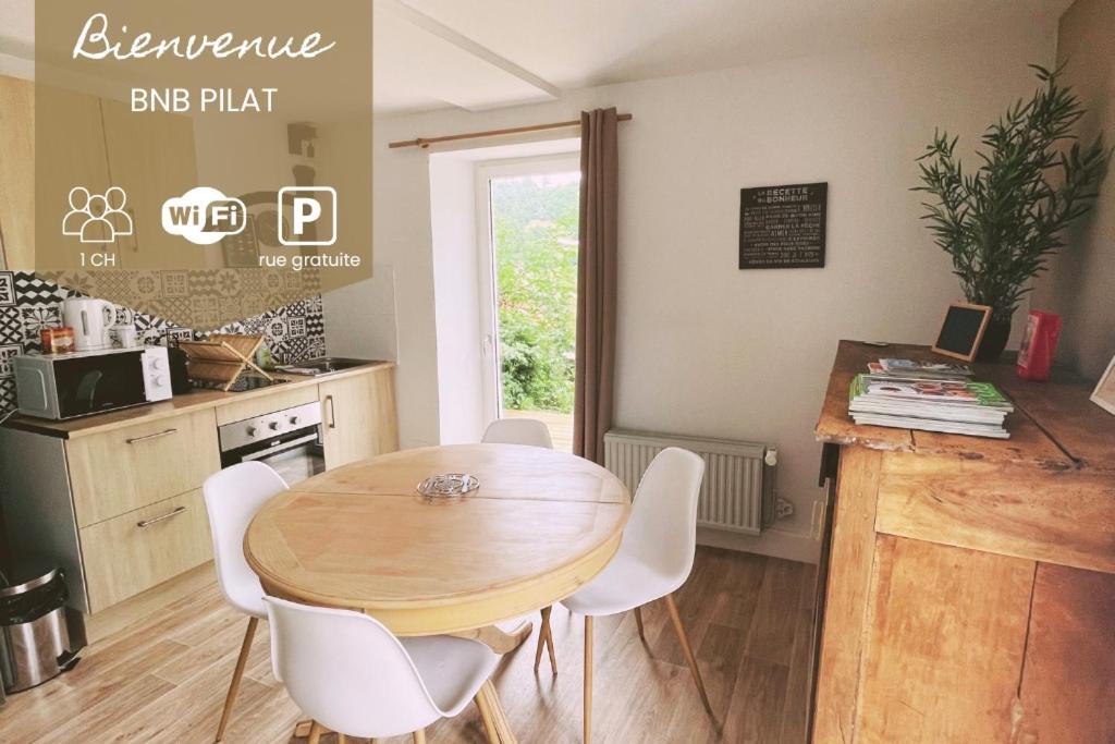 a kitchen with a wooden table and white chairs at PILAT - Charmant T2 rénové dans des anciennes écuries in Saint-Galmier