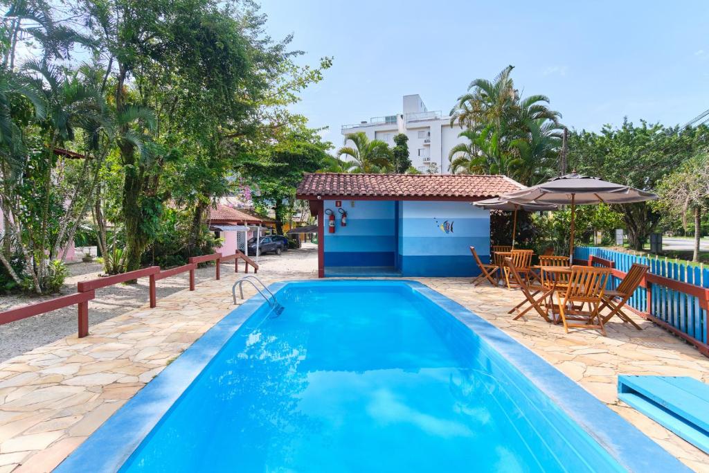 a pool with a table and chairs and an umbrella at Pousada Sanremo Inn in Ubatuba