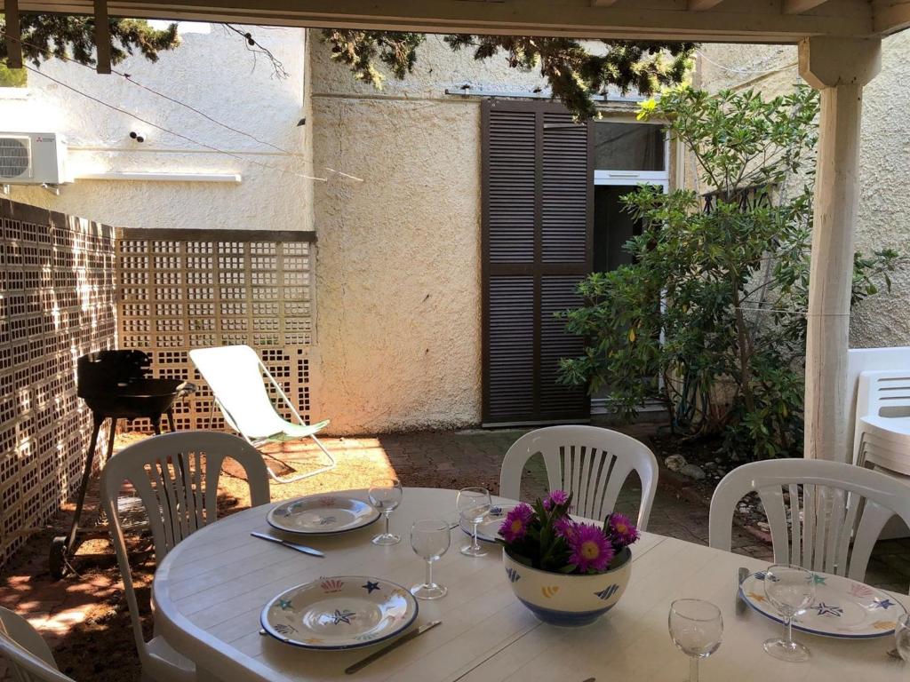 - une table blanche avec des verres et des fleurs sur la terrasse dans l'établissement Villa T4 pour 8 pers. à 350m de la plage avec 3 terrasses, parking privé et équipements complets - FR-1-81-415, à Port-Leucate