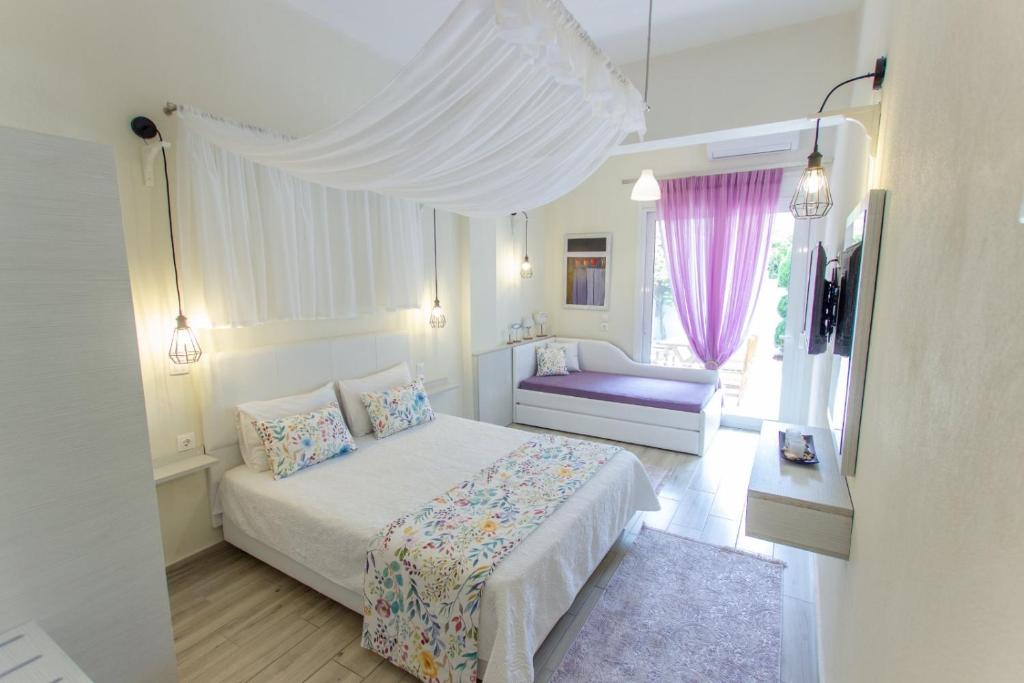 a white bedroom with a bed and a window at Ilion Luxury Studios in Asprovalta