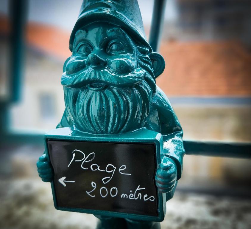 une statue d'un homme tenant une pancarte sur laquelle est écrit « minutes du lieu » dans l'établissement CoeurDeSable - Appartement T3 Hyper Centre Arcachon - Parking, à Arcachon