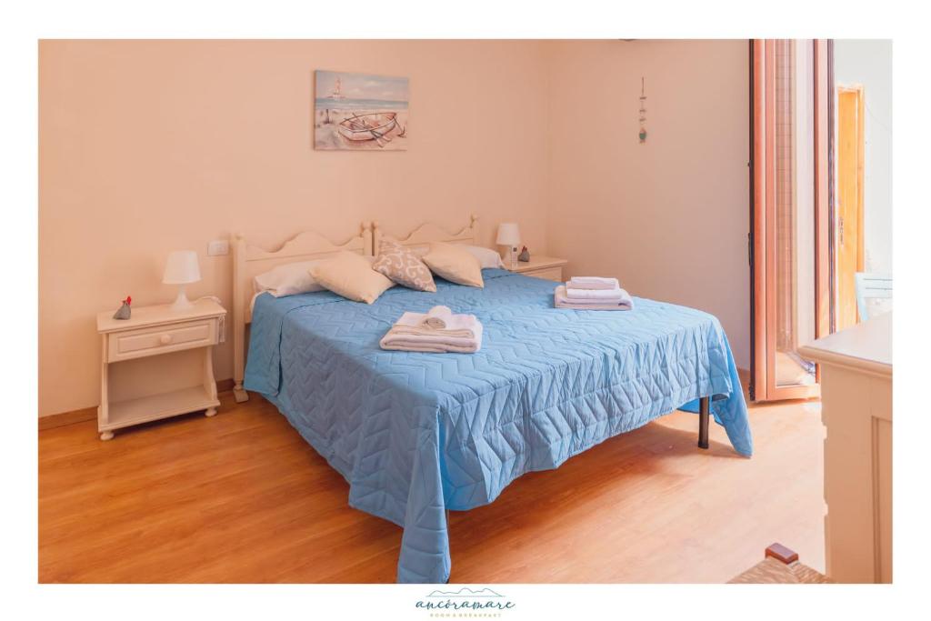 a bedroom with a blue bed with two towels on it at Ancóramare in Stintino