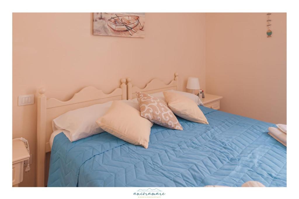 a bedroom with a bed with blue sheets and pillows at Ancóramare in Stintino
